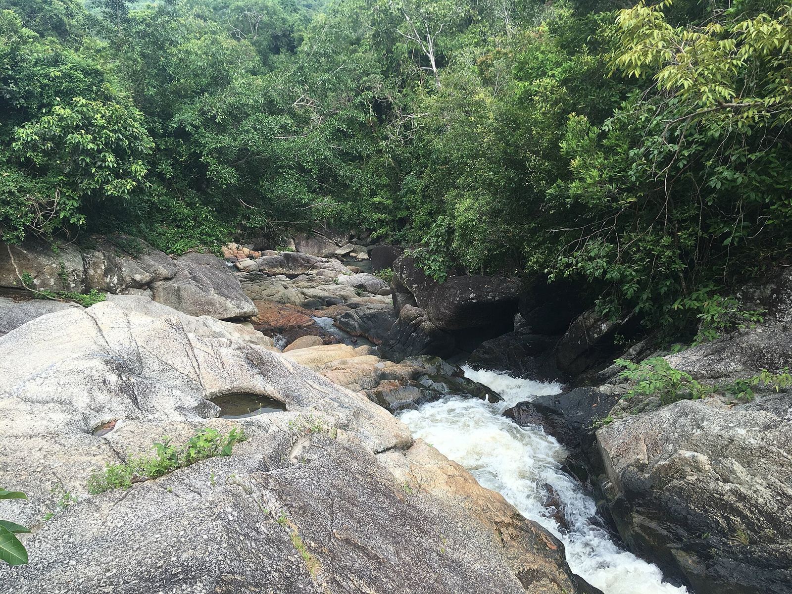 Than Sadet Waterfall flowing over smooth rocks into a pool on the east coast of Koh Phangan