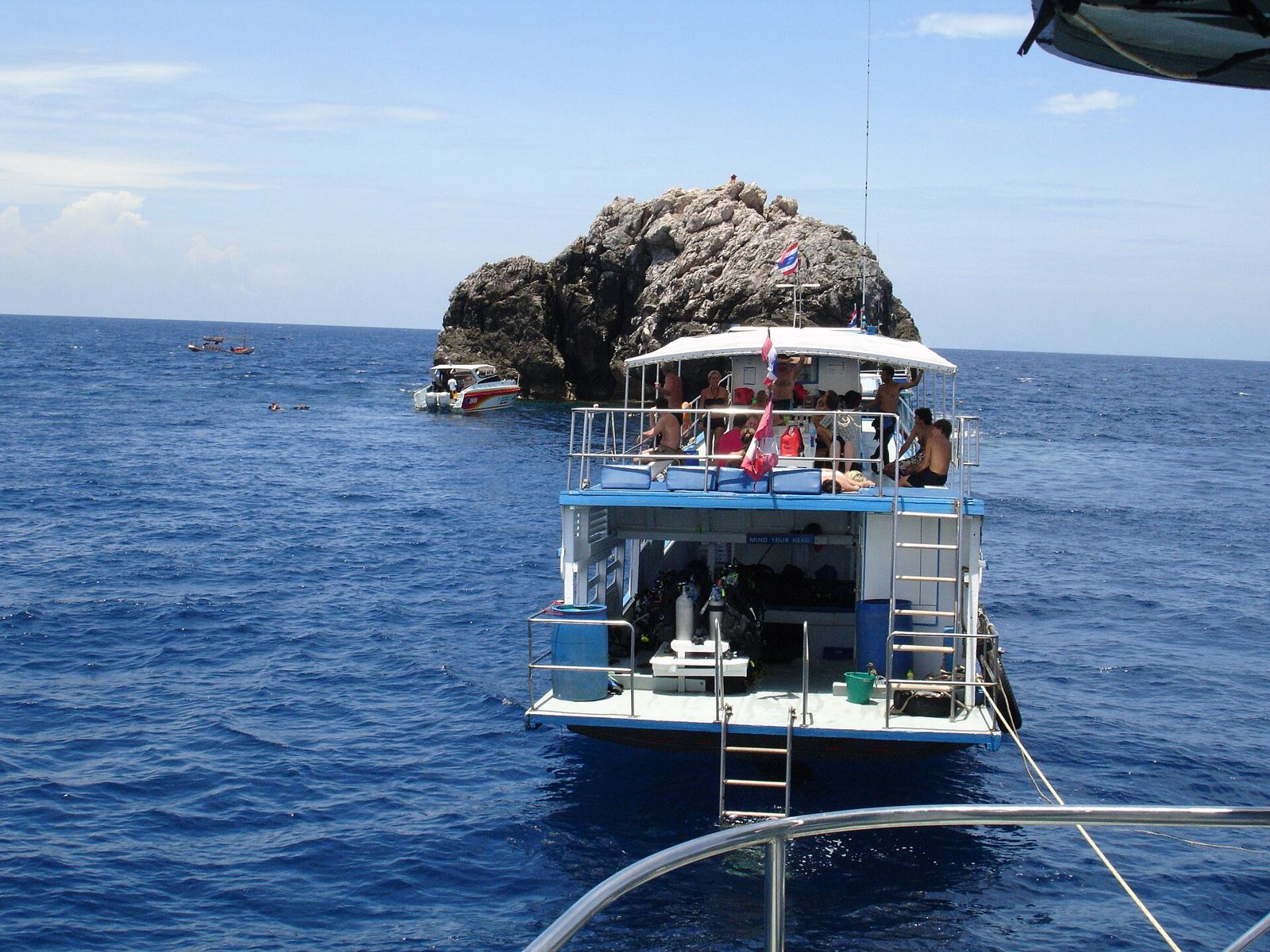 Dive boats moored in a line beside the granite pinnacle of Sail Rock in the Gulf of Thailand
